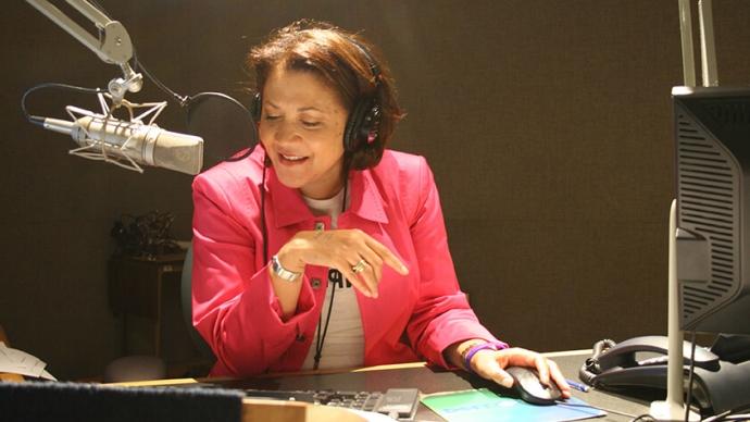 Michele Norris wears headphones while speaking into a microphone inside a studio