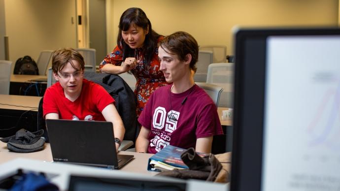 阿花阮 and two students work at a laptop discussing math modeling.
