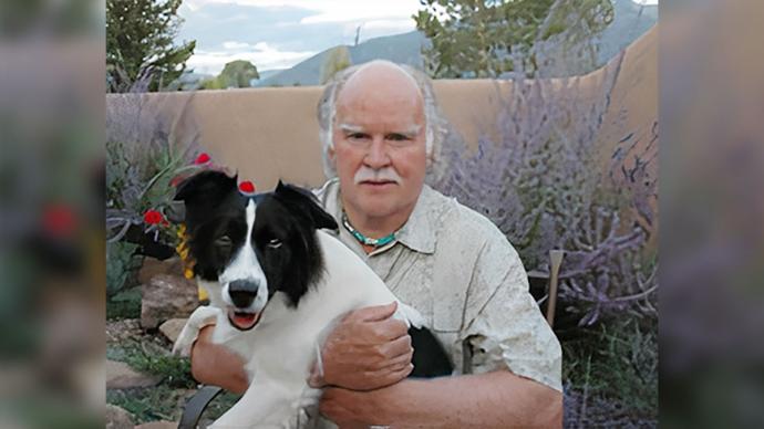 Larry Kimmell holds his dog, New Mexico backdrop