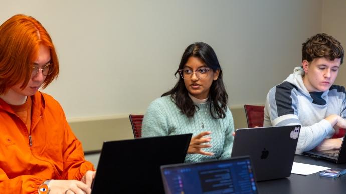 Gaya Rajamony (center) speaks in class while her 同学们 around her work on laptops