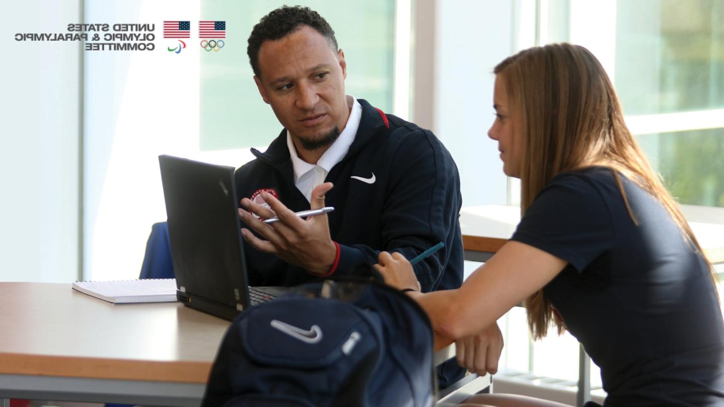 Terris Tiller speaks with an athlete at a table. US Olympic and Paralympic Committee logos in the corner.