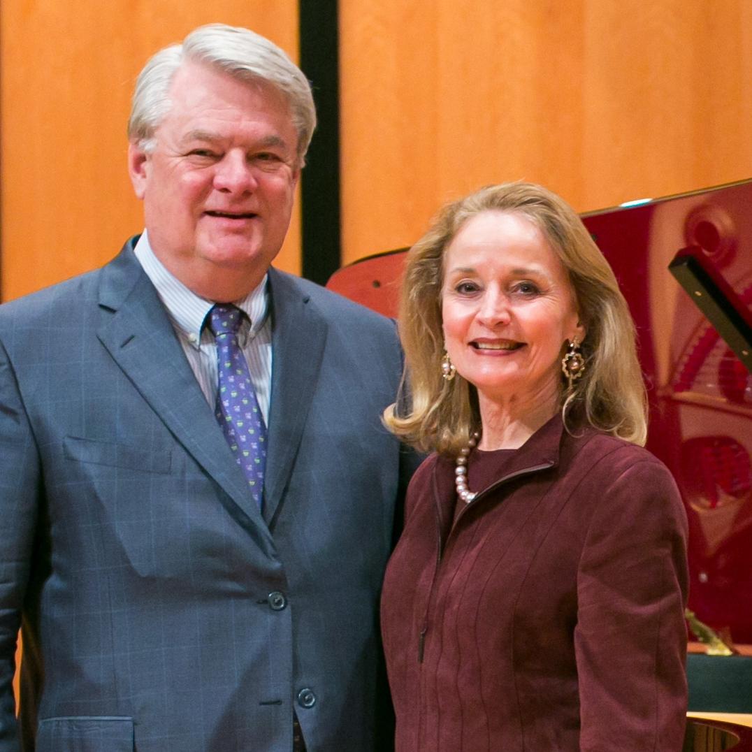 Janet and Jim Dicke stand in front of a maroon Steinway piano in Ruth Taylor Recital Hall