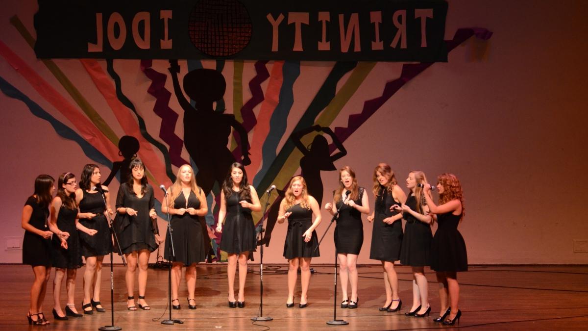 A group of eleven female singers in black dressses perform on stage for 赌博娱乐平台网址大全的偶像.